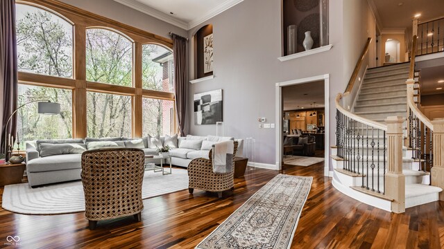 living room with dark wood finished floors, baseboards, a towering ceiling, and stairs