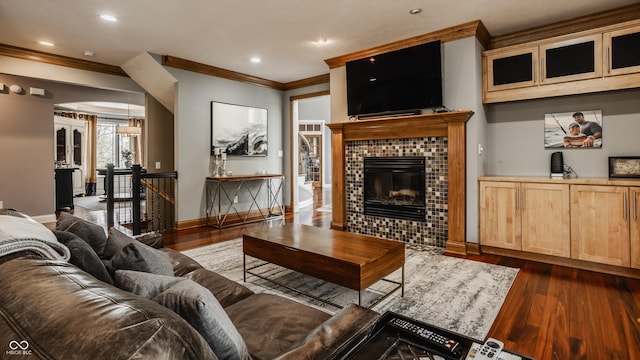 living area featuring dark wood-type flooring, a fireplace, crown molding, and baseboards