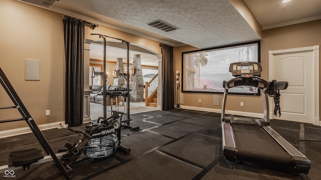 workout room with baseboards, ornamental molding, a textured ceiling, and visible vents