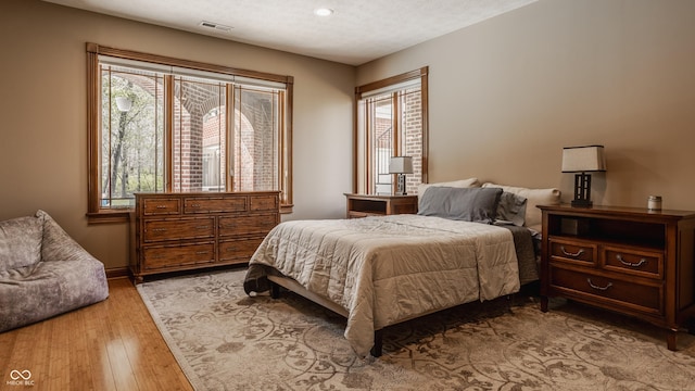 bedroom featuring visible vents, hardwood / wood-style flooring, and multiple windows