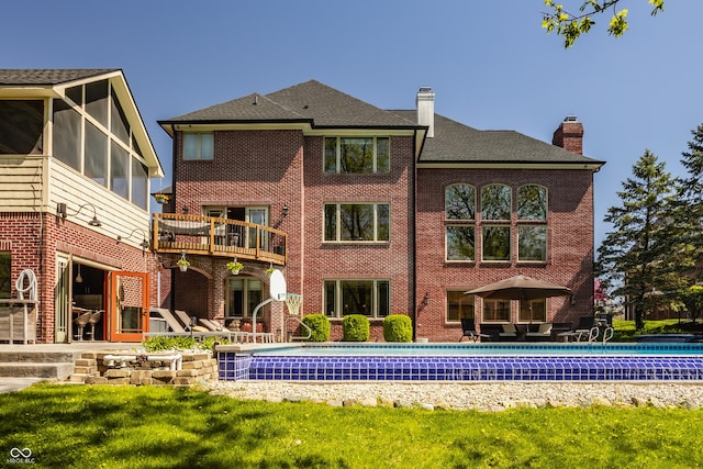 back of property featuring an outdoor pool, a chimney, brick siding, and a patio