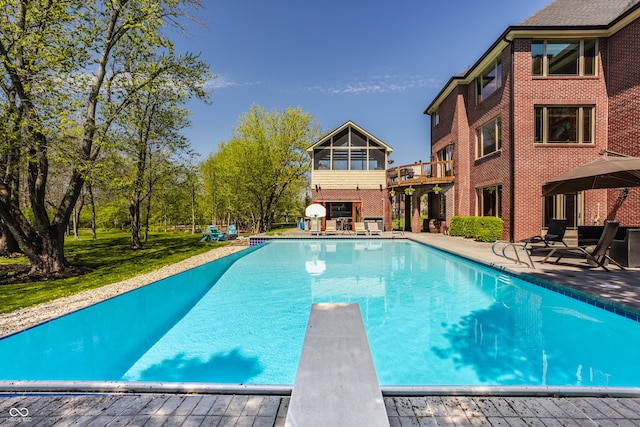 outdoor pool with a diving board and a patio