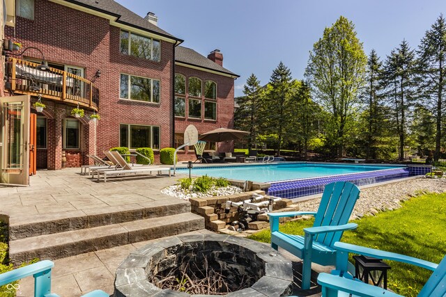 outdoor pool with a patio area and an outdoor fire pit