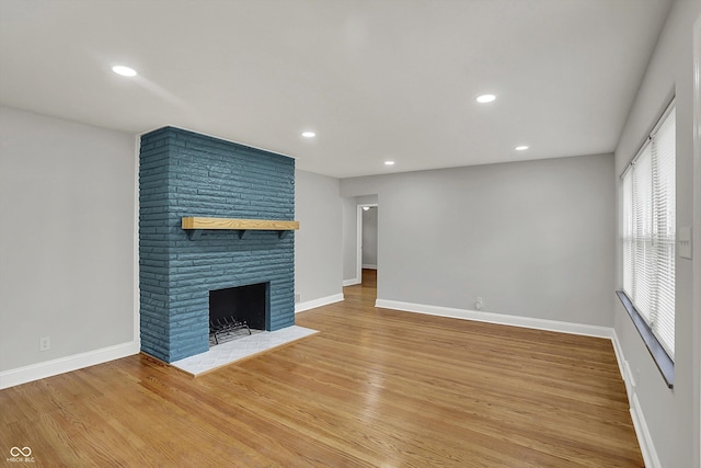 4775 E 56th St, Indianapolis, IN 46220 - unfurnished living room with a large fireplace, light wood-style flooring, and baseboards
