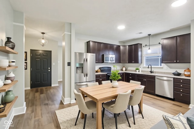 963 Kempson Ct, Westfield, IN 46074 - kitchen featuring appliances with stainless steel finishes, a sink, dark brown cabinetry, light countertops, and light wood finished floors
