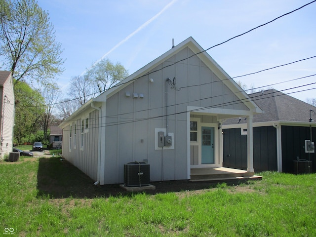 back of house featuring a lawn, central AC, and board and batten siding