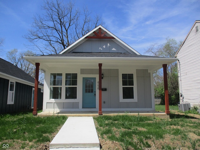 view of front facade featuring board and batten siding, covered porch, and cooling unit