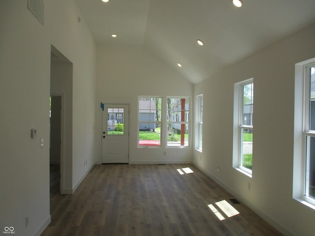 unfurnished living room with healthy amount of natural light, wood finished floors, baseboards, high vaulted ceiling, and recessed lighting