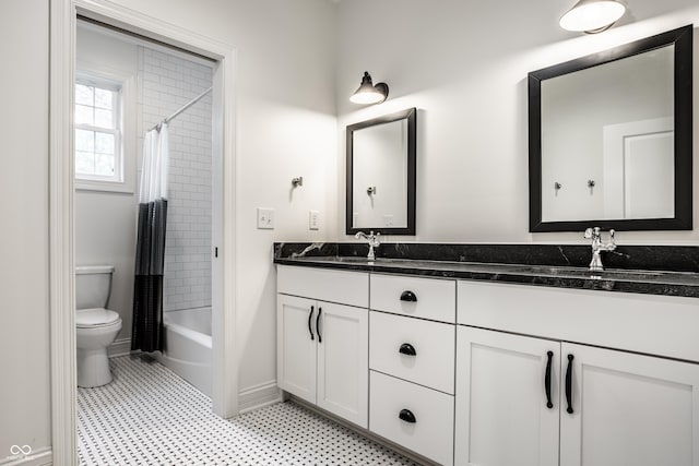 bathroom featuring a sink, double vanity, toilet, tile patterned floors, and baseboards