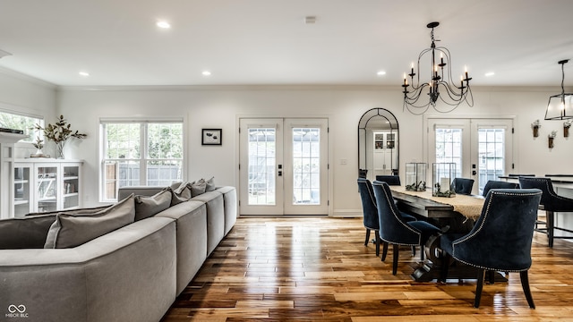 dining area with ornamental molding, wood-type flooring, french doors, and a chandelier