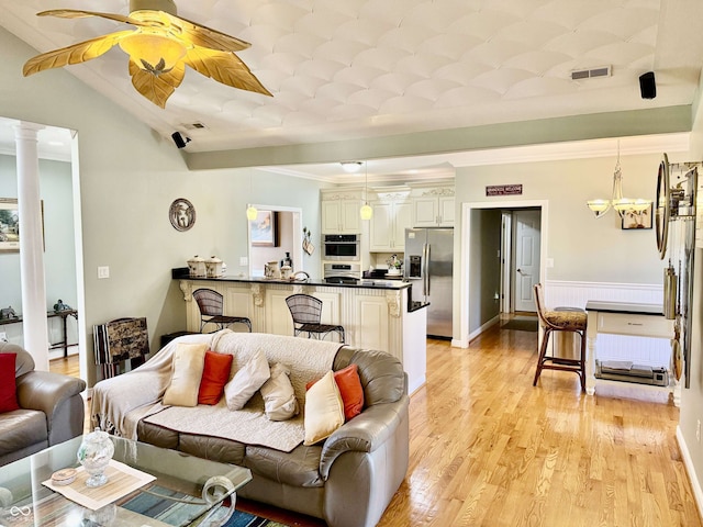 living area with vaulted ceiling, ornamental molding, visible vents, and light wood-style flooring