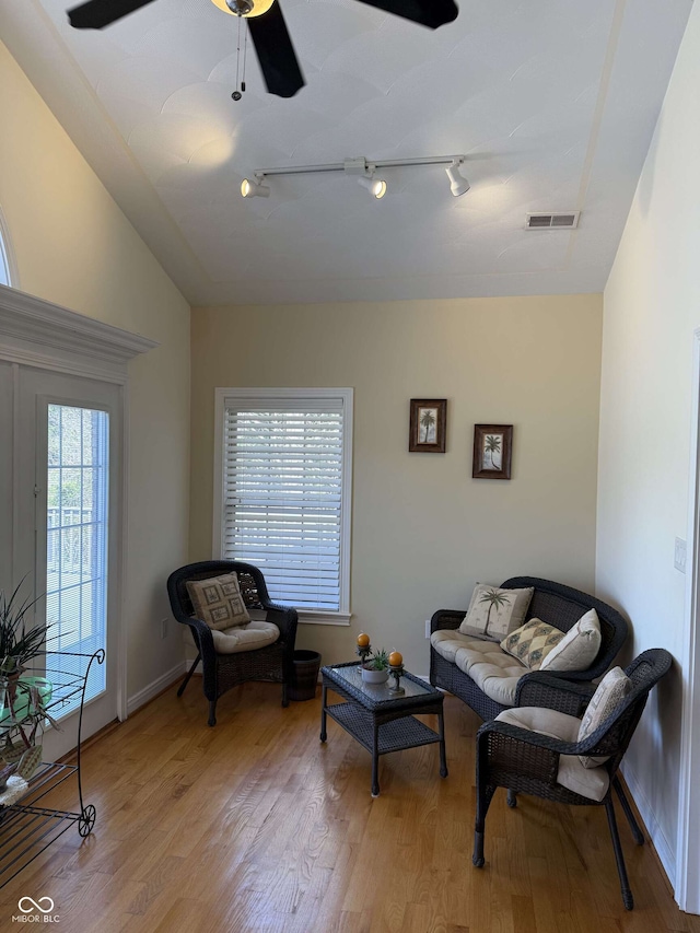 living room featuring track lighting, vaulted ceiling, visible vents, light wood-type flooring, and ceiling fan