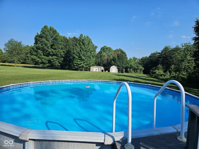 pool featuring a storage unit, a yard, and an outbuilding