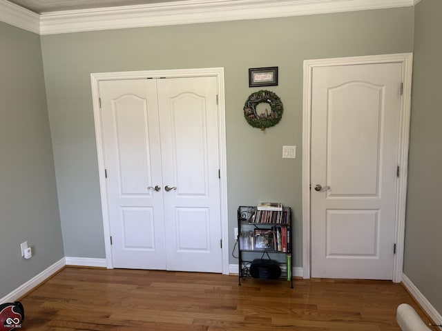 bedroom featuring baseboards, wood finished floors, a closet, and ornamental molding