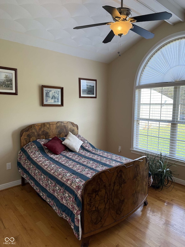 bedroom with baseboards, a ceiling fan, wood finished floors, and beam ceiling