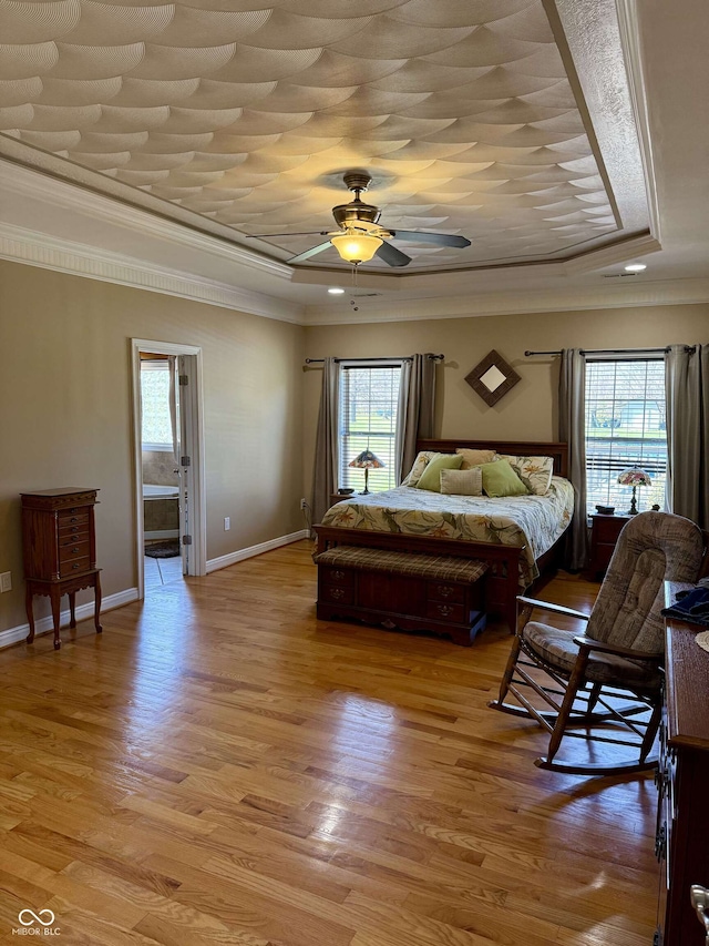bedroom with ornamental molding, light wood-style flooring, multiple windows, and a raised ceiling