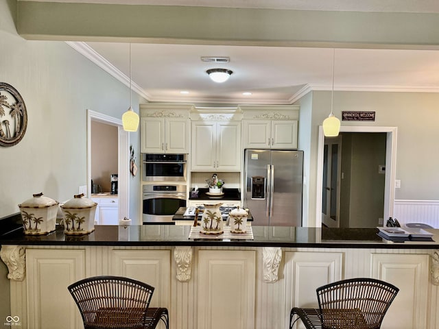 kitchen with visible vents, crown molding, a breakfast bar area, and stainless steel appliances
