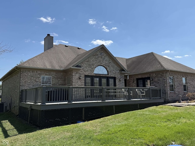 back of property featuring brick siding, a yard, and a wooden deck
