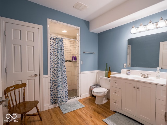 full bath featuring toilet, wood finished floors, a stall shower, wainscoting, and vanity