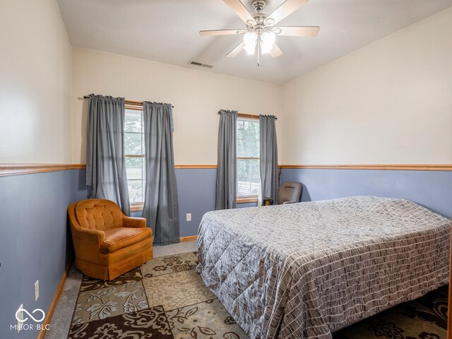 carpeted bedroom with baseboards, multiple windows, and a ceiling fan