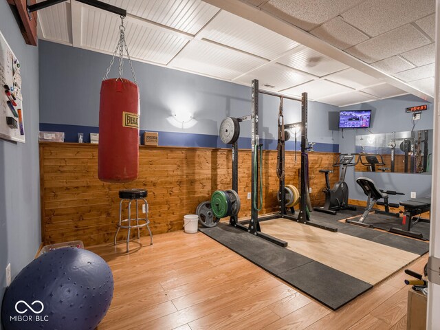 workout room featuring wood-type flooring, wooden walls, and wainscoting