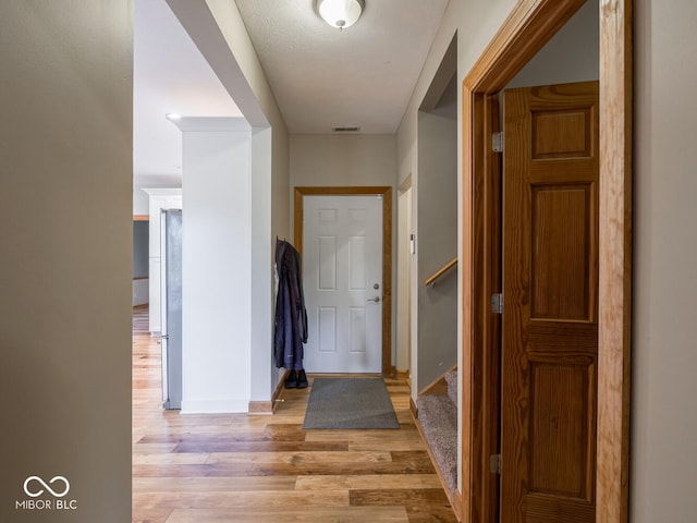 foyer entrance with light wood finished floors, stairs, and baseboards