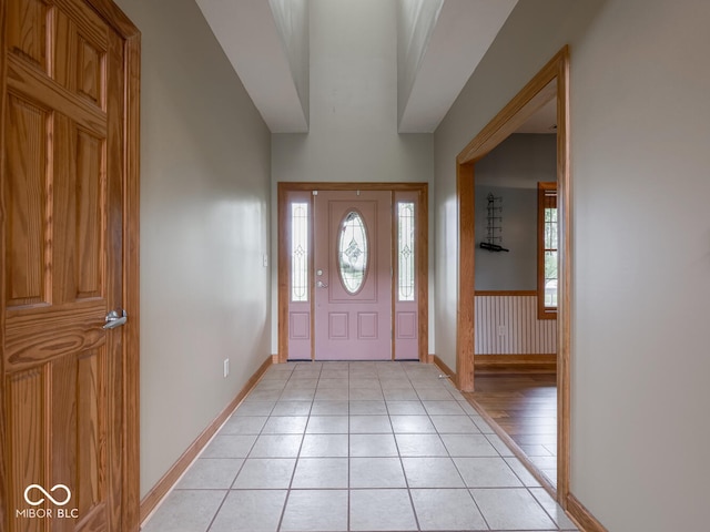foyer featuring baseboards, light tile patterned floors, and a wainscoted wall