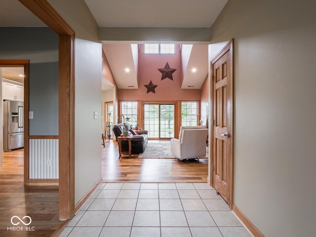 hall with light wood-type flooring, lofted ceiling, recessed lighting, and baseboards