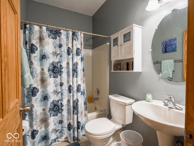 bathroom featuring toilet, shower / bath combo with shower curtain, and a sink