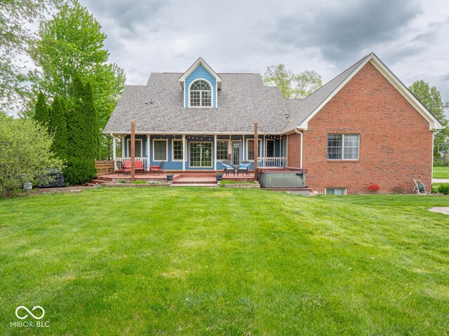 rear view of property with a hot tub, a yard, brick siding, and a shingled roof