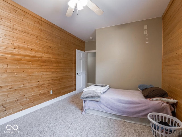 bedroom featuring wooden walls, carpet floors, and a ceiling fan
