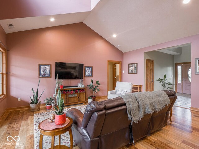 living area with high vaulted ceiling, light wood finished floors, and recessed lighting