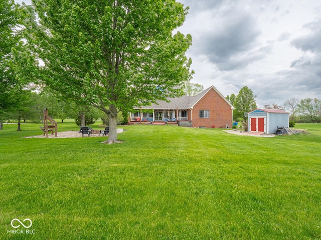 view of grassy yard with a storage unit, an outdoor fire pit, and an outbuilding