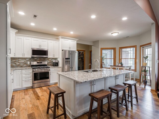 kitchen with stainless steel appliances, a sink, a breakfast bar, tasteful backsplash, and recessed lighting