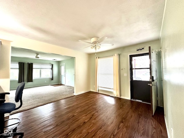 interior space with visible vents, ceiling fan, baseboards, and dark wood-type flooring