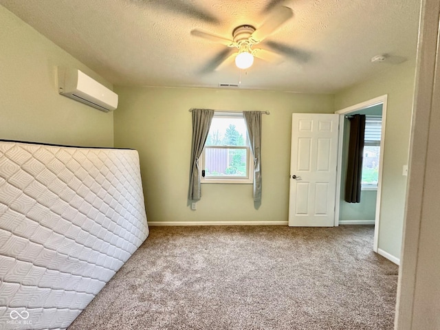 unfurnished bedroom with a textured ceiling, carpet flooring, visible vents, baseboards, and an AC wall unit