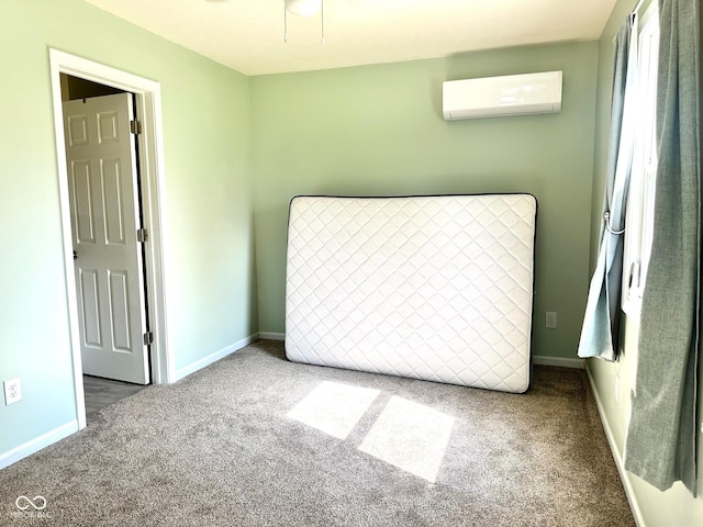 unfurnished bedroom with baseboards, a wall mounted air conditioner, and carpet flooring