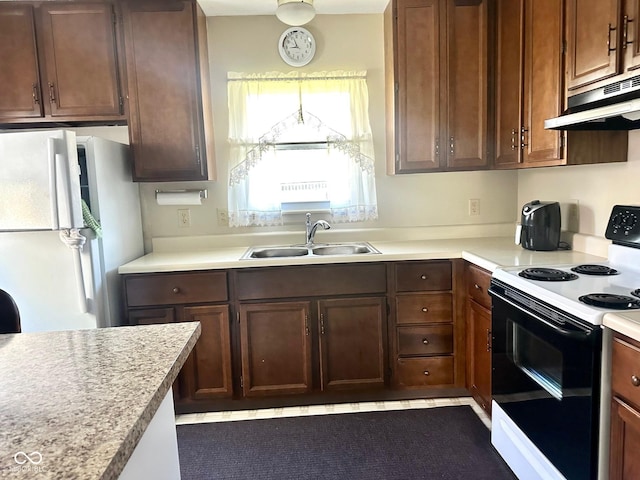kitchen with freestanding refrigerator, electric range, under cabinet range hood, light countertops, and a sink