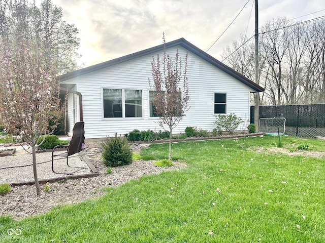 view of side of home featuring fence and a yard