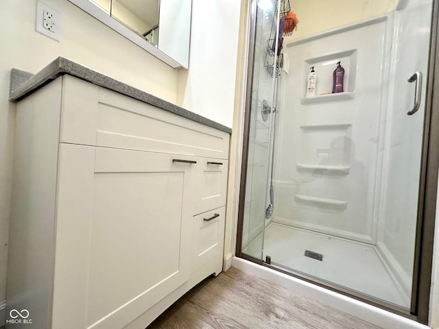bathroom with a stall shower and wood finished floors