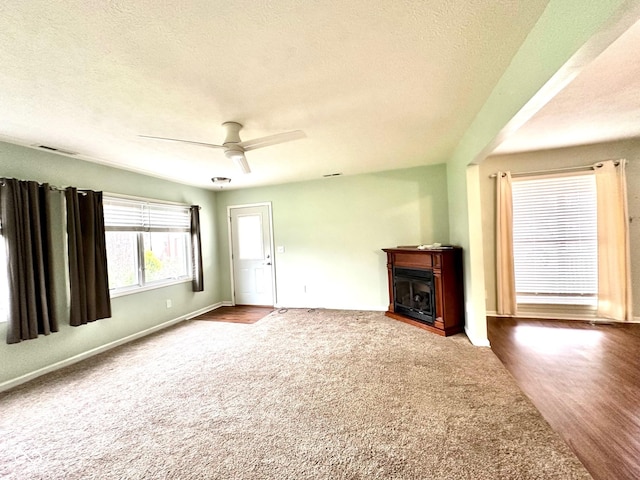 unfurnished living room with carpet flooring, ceiling fan, a textured ceiling, and a fireplace