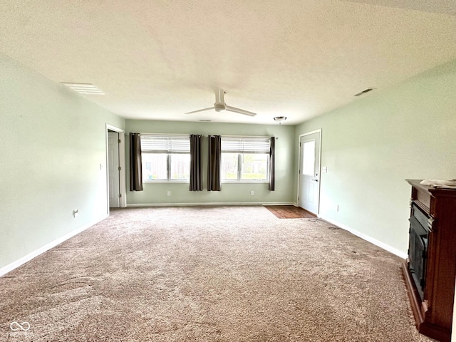 unfurnished living room with a ceiling fan, a textured ceiling, carpet, and baseboards