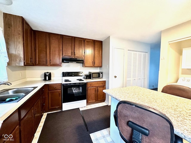 kitchen featuring stainless steel microwave, range with electric cooktop, under cabinet range hood, light countertops, and a sink