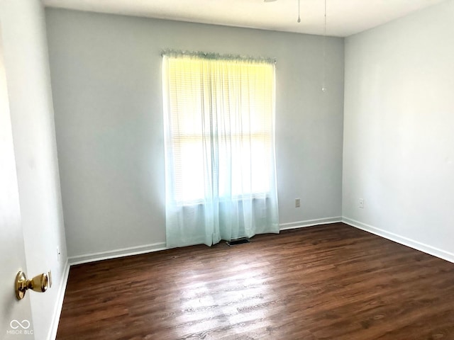 spare room featuring baseboards and dark wood-type flooring