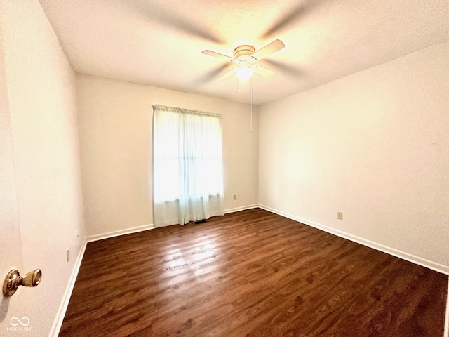 unfurnished room featuring dark wood-type flooring, a ceiling fan, and baseboards