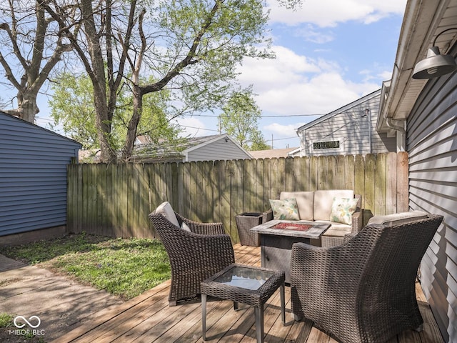 deck with an outdoor living space with a fire pit and fence