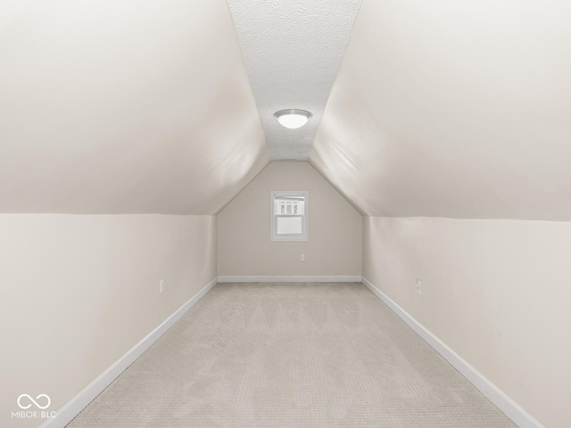 bonus room featuring baseboards, vaulted ceiling, and light carpet