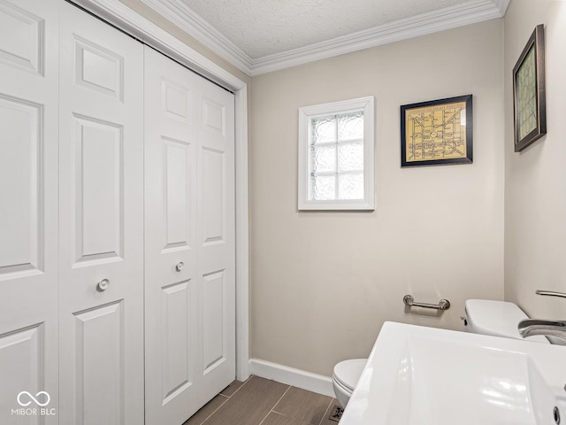 bathroom with a sink, baseboards, a closet, toilet, and ornamental molding