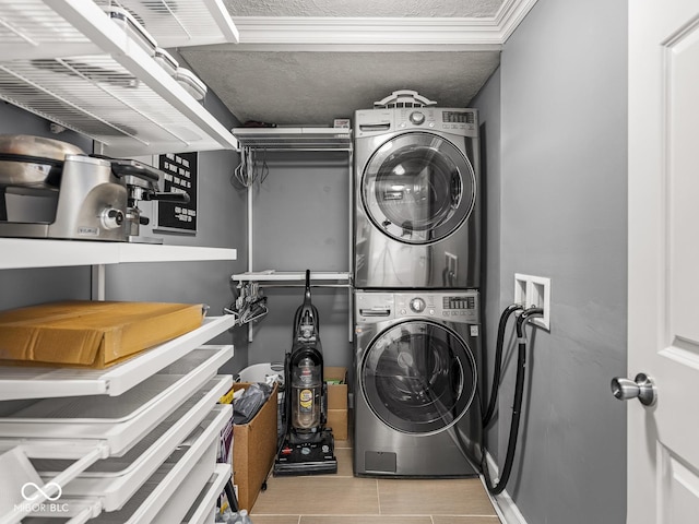 clothes washing area with tile patterned flooring, stacked washer / drying machine, and laundry area