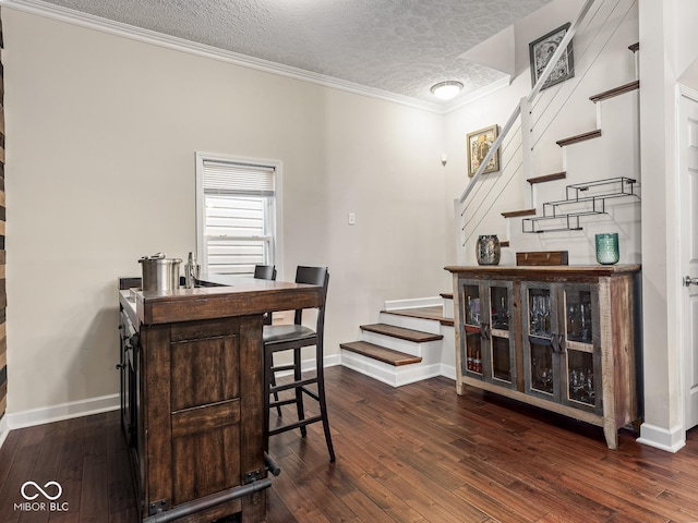 dining space featuring a textured ceiling, baseboards, dark wood-type flooring, ornamental molding, and stairway